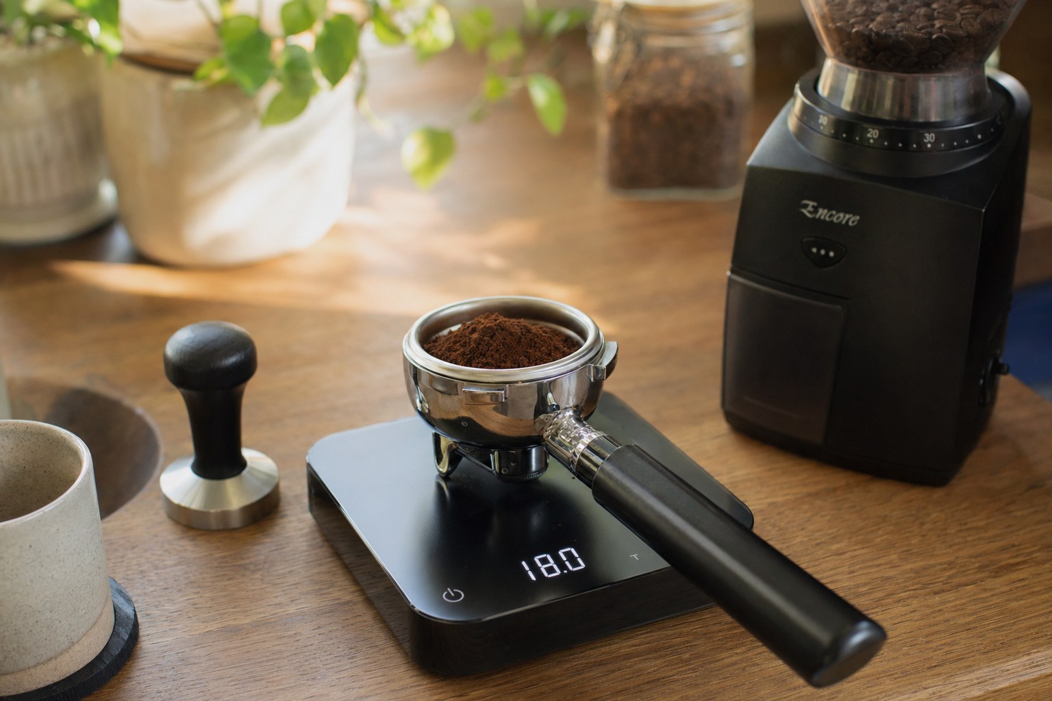 Portafilter on an Acaia Pearl scale showing 18.0g dose, Baratza Encore grinder in background on kitchen counter